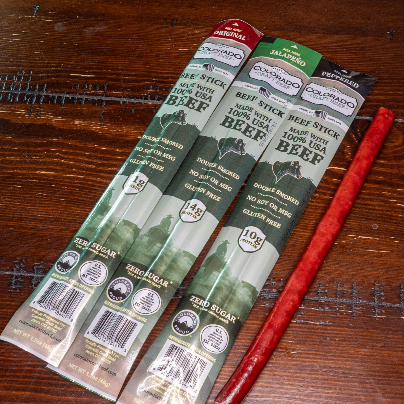 Three packages of beef sticks on a wooden surface